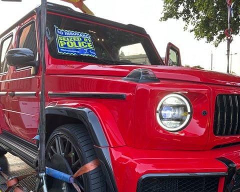Red Mercedes Benz G-wagon with its wheels clamped loaded on to a towing vehicle