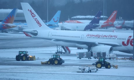 Staff use tractors to help clear snow from around aircraft at Manchester airport.