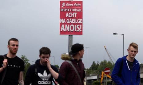 People walk past a poster calling for an Irish language act in Belfast, Northern Ireland