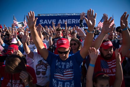 Crowd with hands raised and heads down in prayer.