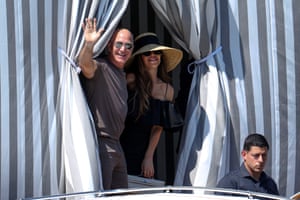 Jeff Bezos and Lauren Sanchez Bezos wave from within a striped tent