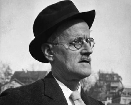 Black and white photo of man in round spectacles and hat, wearing a suit and tie.