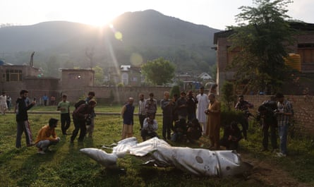 People stand near the damaged part of an unidentified aircraft at a Mosque compound in Pampore, in the outskirts of Srinagar, in Indian-administered Jammu and Kashmir.