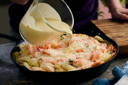 Saus krim dituangkan di atas wajan berisi sayuran panggang