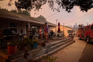 A homeowner sprays down his house as the glow from the canyon fire is visible in the background.