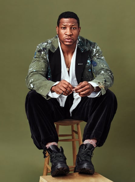 Jonathan Majors wears blazer, shirt and trousers by Greg Lauren, shoes by Jimmy Choo, lapel pin and ring by Darkai.