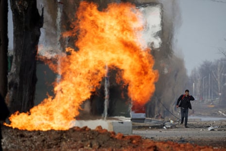 A man walks past a burning gas pipeline that was hit during shelling in a neighbourhood in northern Kharkiv.