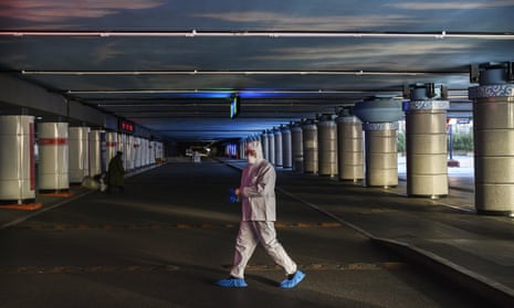 A Chinese railway worker wears a protective suit as he walks across empty taxi lanes at Beijing West Railway Station on 16 February.