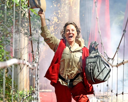 Esther Rantzen running across a drawbridge waving a hat and carrying a bag