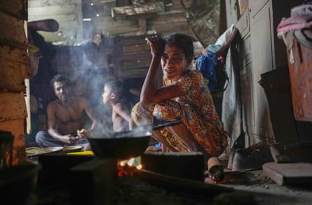 A woman sits by the fireplace at meal time in a shanty in Colombo.
