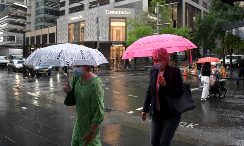 People walk in Sydney’s city centre as rain falls