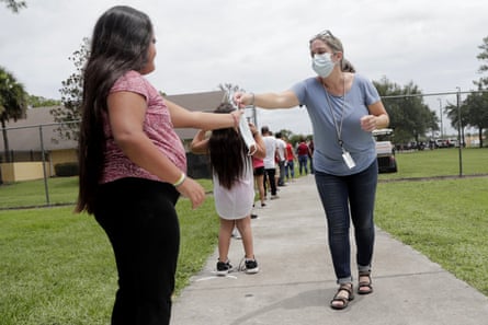 A woman passes out masks to people standing in line for Covid testing in Immokalee, Florida, on 7 June 2020.