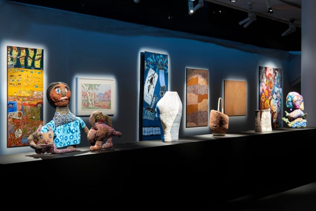 An installation at Natsiaa 2022 featuring figures displayed in cases in front of poster drawings