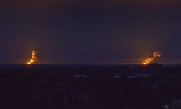 Two simultaneous explosions are visible in the distance from a massive Russian missile attack on Ukrainian infrastructure.
