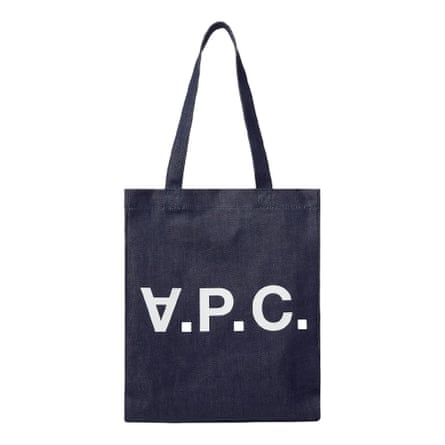 A navy tote bag. There are there are three large letters printed on the middle of the bag whit are A. P. C. and the A is upside down. It is on a white background.