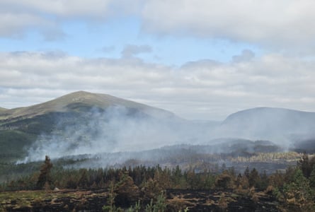 Smoke rising above wooded hills.