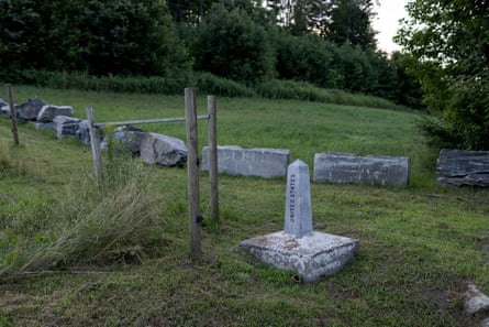 A concrete obelisk marks in a green field with a forest in the background.