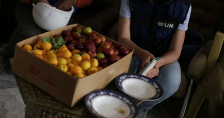UN and World Food Programme staff sit beside a box of fruits in eastern Ghouta, in the Syrian capital Damascus.