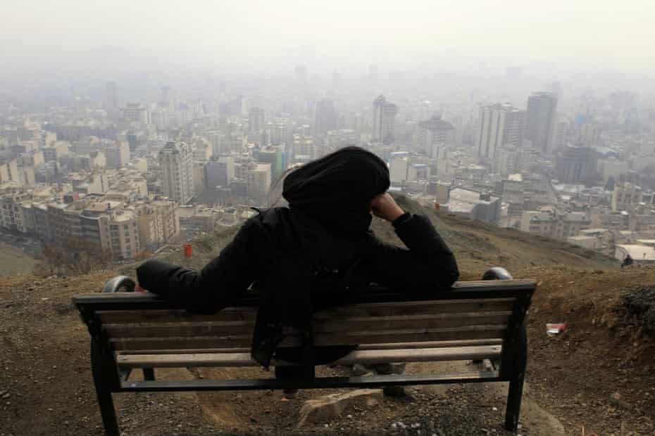 A woman in Tochal looks out at the polluted skyline of the Iranian capital, Tehran.