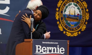 Ilhan Omar embracing Bernie Sanders on a podium during his presidential campaign.