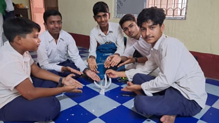 A group of male students sit in a circle on the floor