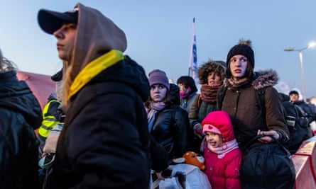 Ukrainians line up to get on buses headed across the Polish border, 18 March.