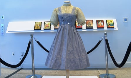 A blue and white checked gingham dress, worn by Judy Garland in 1939 film, hangs on display.