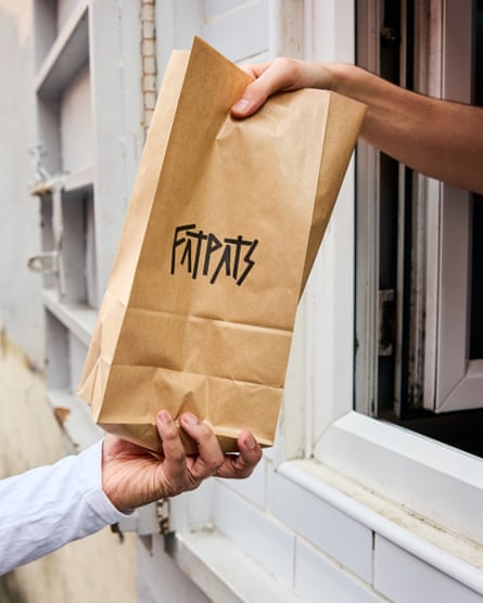 A paper bag emerges through a window to hand to a customer at Fat Pats, Manchester.