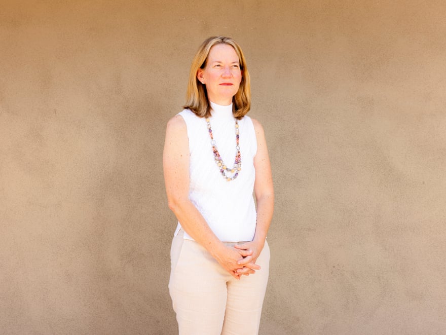 A woman in white against a beige wall