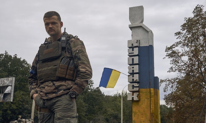Ukrainian soldier stands in front of a Kupiansk sign