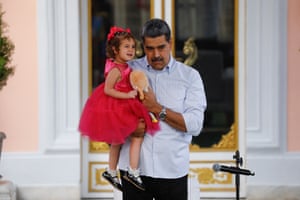 Nicolas Maduro carries a child in a red dress and her doll