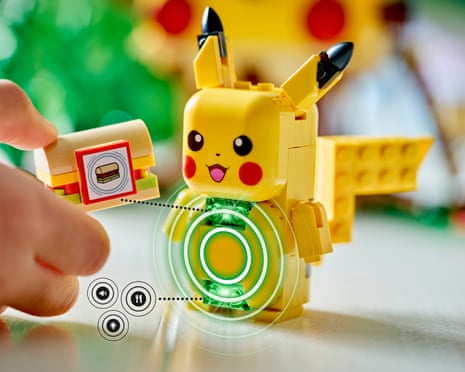 A hand holds a Lego Pikachu figure with digital interface graphics overlaid on the image