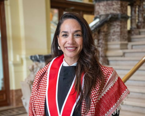 Woman smiles wearing a red and white scarf over an academic robe