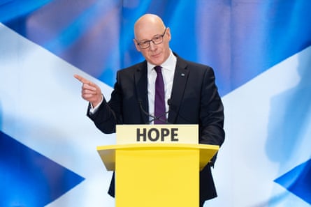 John Swinney stood on stage behind a lectern with 'hope' on it