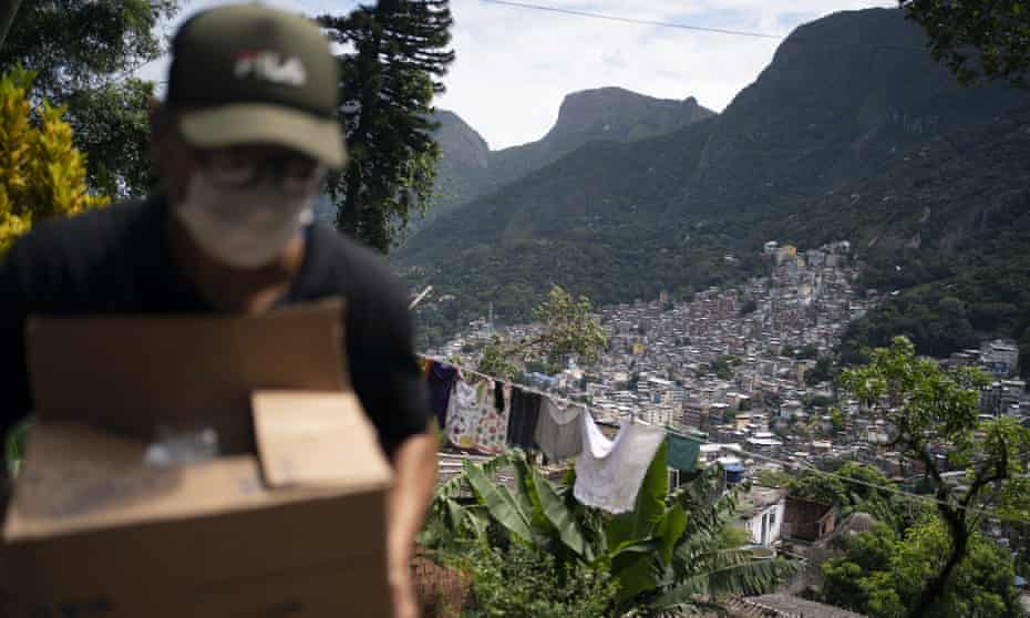 A local volunteer carries a package in the Rocinha favela. Brazil’s death toll from coronavirus has risen in recent days.