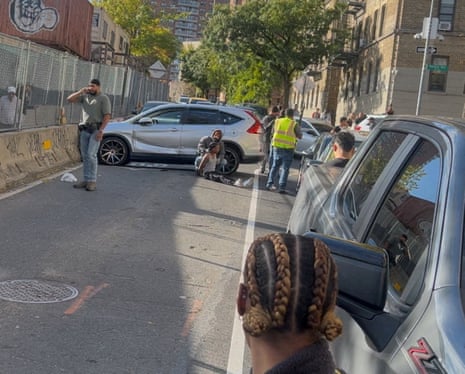 A detained man sits on the ground after a shooting involving ICE officers in the Bronx