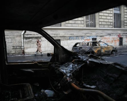 A woman walks past burned-out cars in Paris.