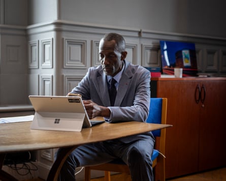 Mayor of Saint-Denis sits at a desk with a tablet and types.