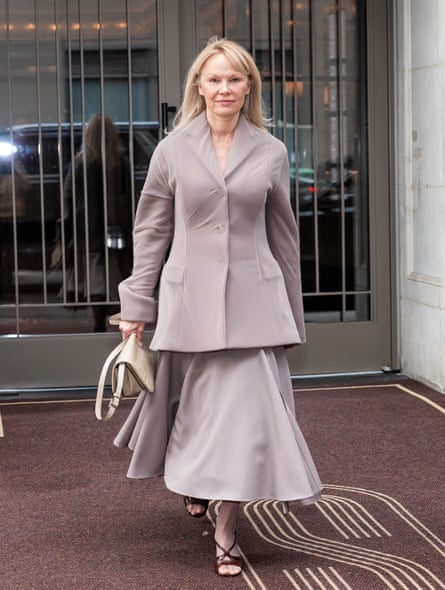 Pamela Anderson wearing a long circular skirt and long flared jacket, with minimal makeup