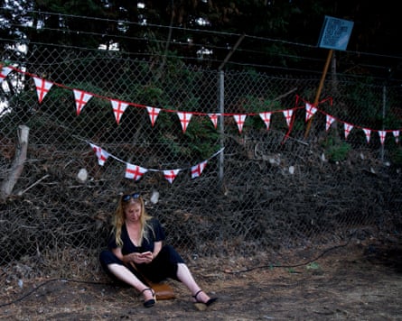 A woman sits against a fence outside RAF Barnham while on a march