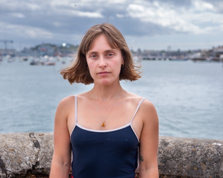 Hannah Cocks stands in front of a low wall on the waterfront