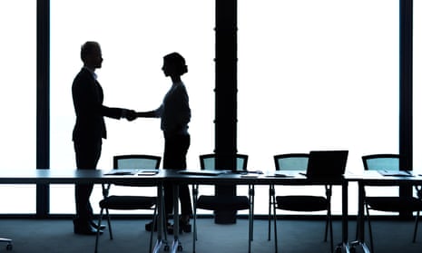Silhouetted man and women shaking hands in boardroom