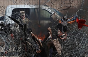 Members of the Texas national guard set fire to clothing on a barbed wire fence