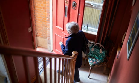 An older woman opening a front door to leave the house