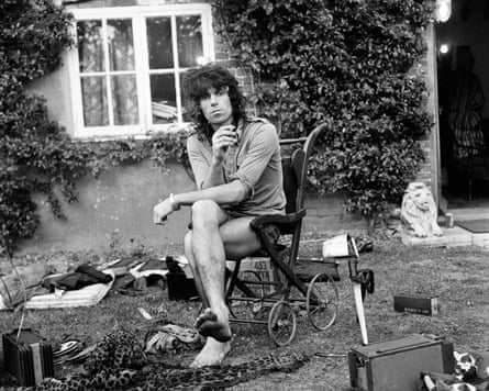 Keith Richards sitting smoking on a wheelchair with objects strewn about