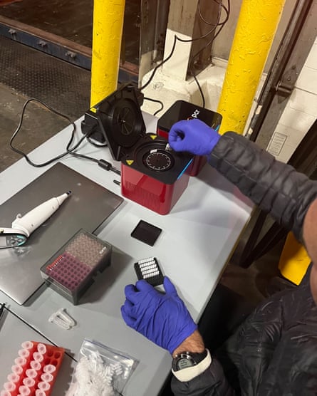 Gloved hands set up testing equipment on a desk