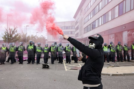 İngiltere'de, 4 Ağustos 2024'te Rotherham'da bir oteli polis memurları korurken bir adamın elinde duman fişeği tutması sonucu çıkan huzursuzluk.