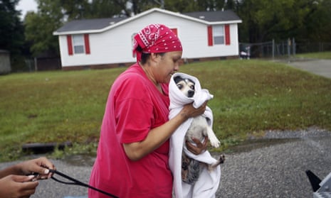 Cynthia Capers carries her dog Lougie while being evacuated into a high water vehicle by the police as their neighborhood begins to flood from Florence in Fayetteville, North Carolina