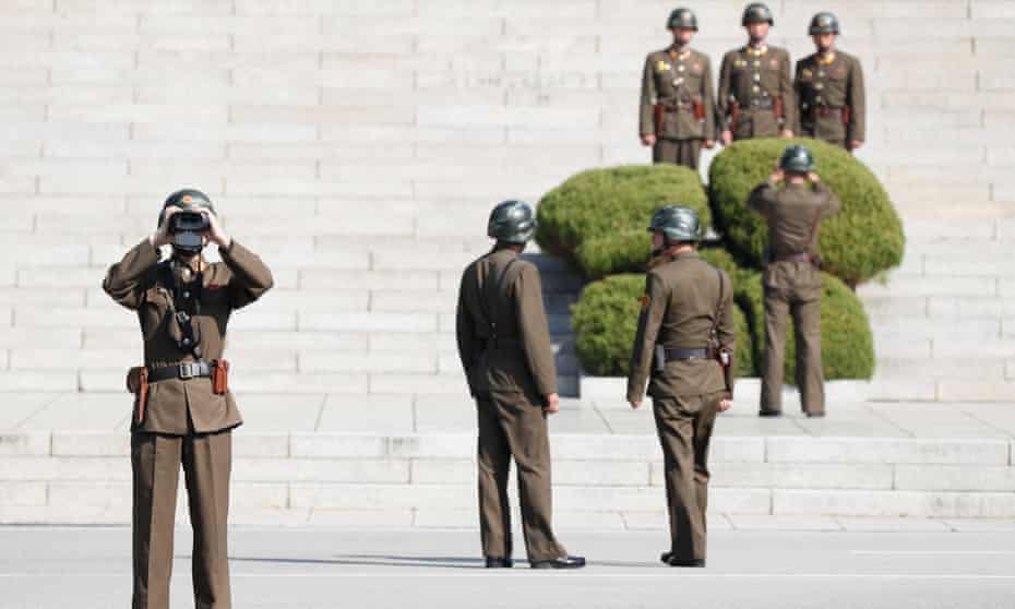 A North Korean soldier looks through binoculars towards the border village of Panmunjom in Paju, South Korea
