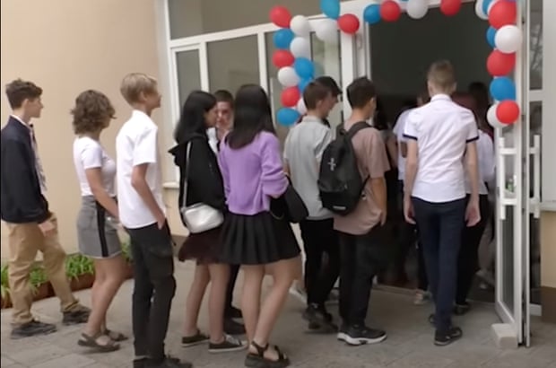 Pupils walk through a door decorated with balloons in the colours of the Russian flag in Kherson, Ukraine